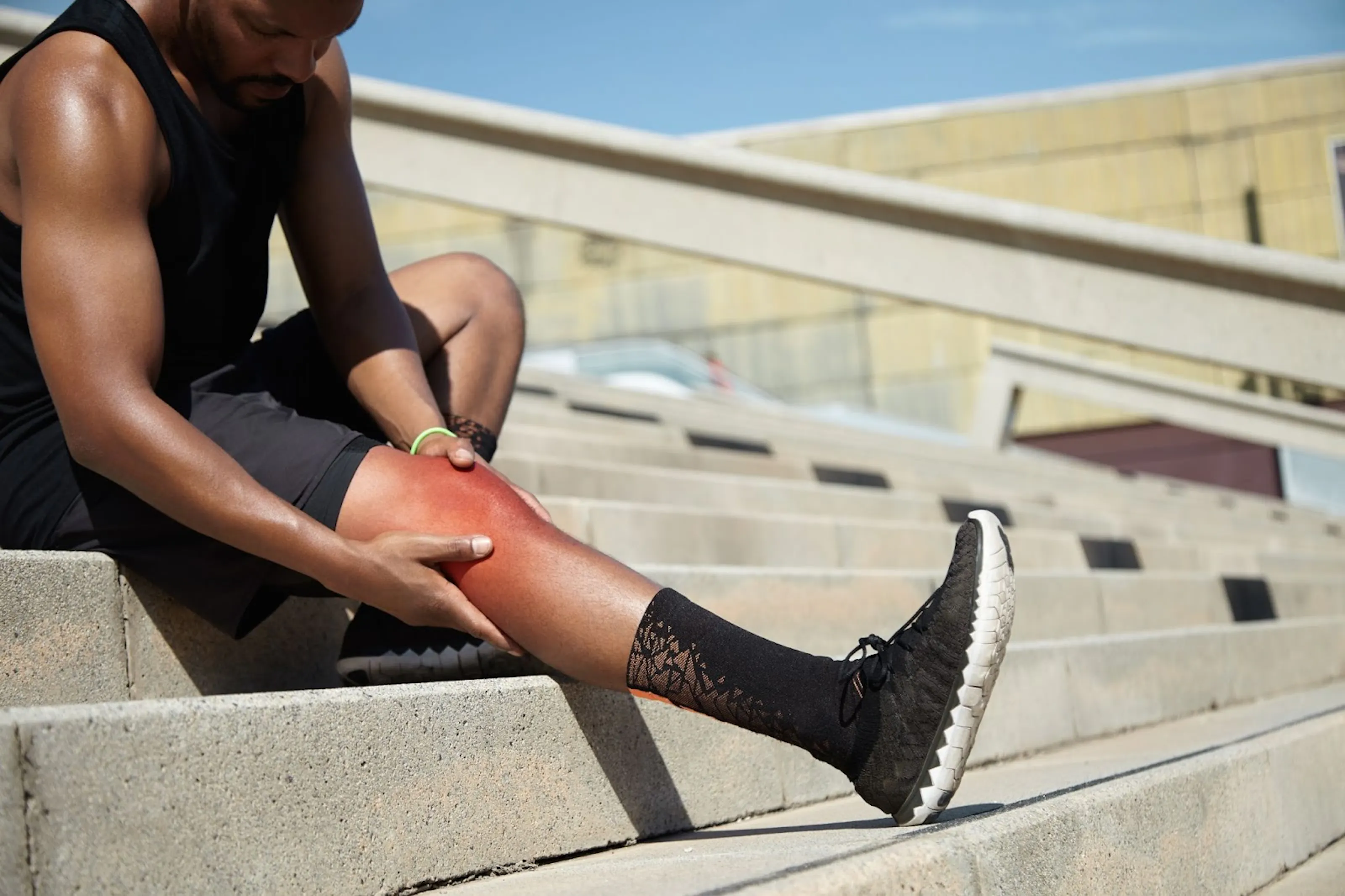 An athlete holding their knee as they experience knee pain from running.